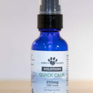 blue bottle of earth buddy water soluble cbd for dogs and cats with blue sticker on a wood table