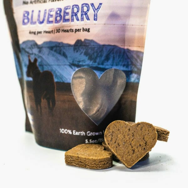 bag of earth buddy Blueberry Hemp Heart cbd dog treats with a heart shaped biscuits piled next to bag
