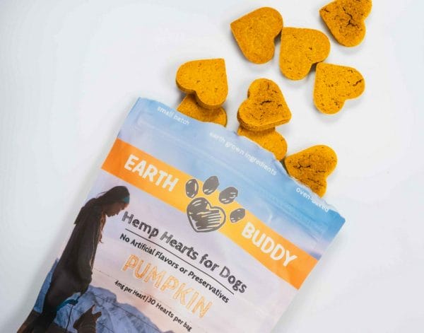 open bag of earth buddy pumpkin cbd treats for dogs with heart shaped biscuits spilled out of bag