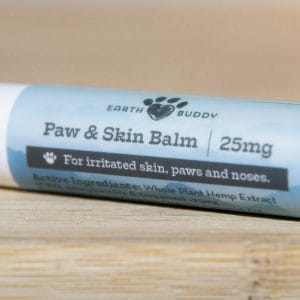 Small trial-size tube of Earth Buddy hemp dog skin balm for dry skin, paws, and noses on a table.
