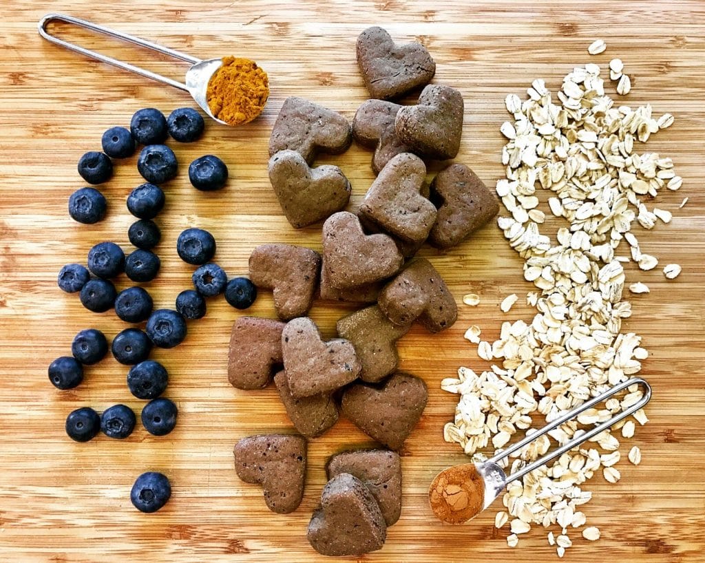 ingredients spread out on a cutting board. Blueberries, oats, turmeric, and cinnamon are healthy ingredients pet owners can look for in dog food.