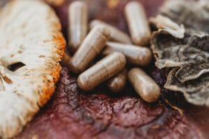 Mushroom capsules for dogs and cats on top of raw reishi, turkey tail, and lion’s mane mushrooms to antioxidant properties of mushrooms for pets.