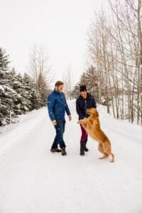 Golden Retriever jumping on a man & woman on a snowy day in CO. This blog gives tips on how to soothe irritated dog paws