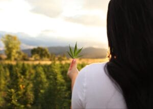 Woman holding a hemp leaf on Earth Buddy’s organic hemp farm in CO. Learn more about cannabis dog treats & supplements.