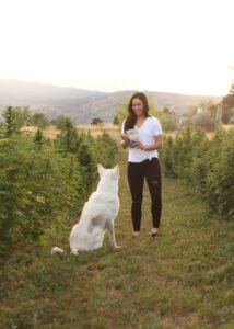 Woman giving a white german shepherd some of Earth Buddy’s CBD treats for dogs on their organic hemp farm in colorado. 