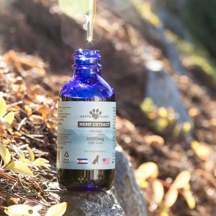 Bottle of Earth Buddy’s best CBD oil for dogs with dropper of full spectrum hemp extract dripping back into the bottle.