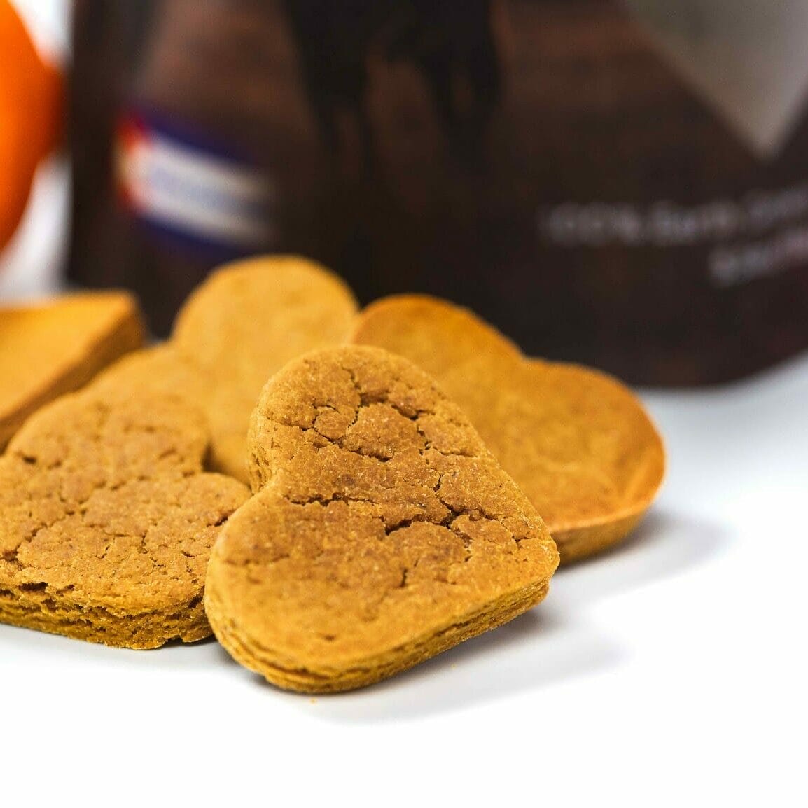 Earth Buddy Pumpkin CBD treats for dogs in a pile next to a pumpkin and bag of Hemp Hearts. Earth Buddy CBD treats for dogs are a great limited ingredient treat option for dog anxiety.