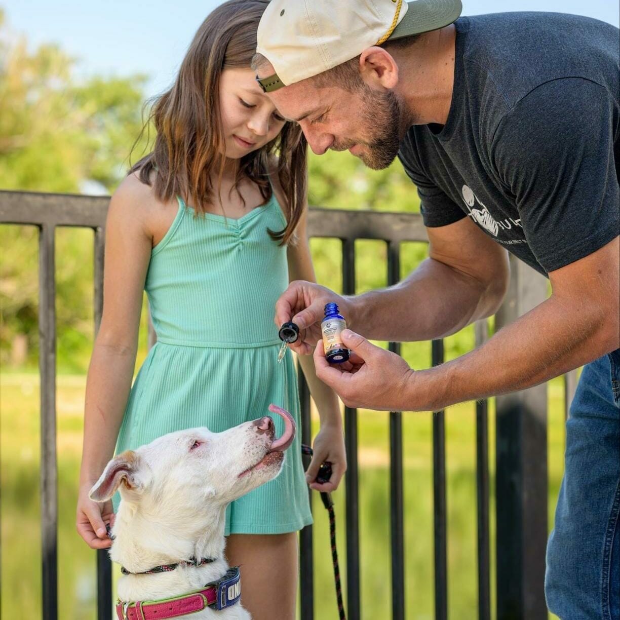 Earth Buddy founder, Sean Zyer and his daughter giving Cellular Support 500mg CBG Extract to white dog with brown spots. CBG for dogs helps with IBS and seizures.